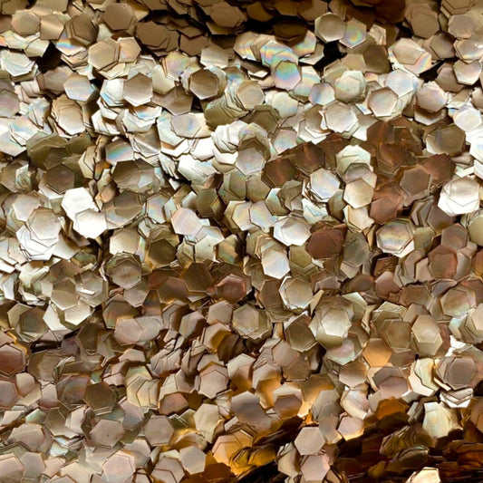 A close-up image of rose gold super chunky eco glitter, showing the reflective and sparkling surface.