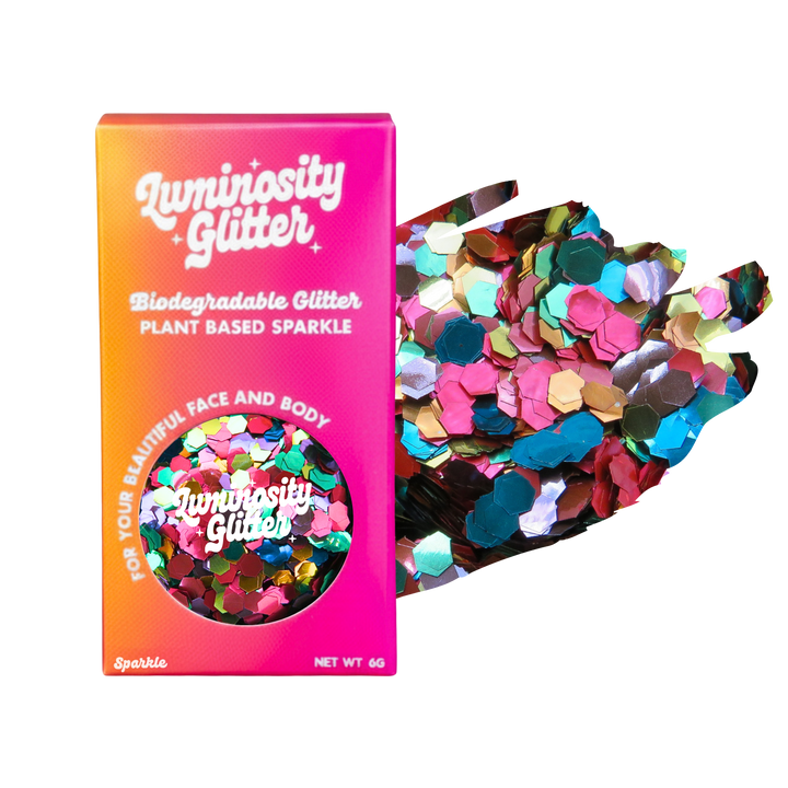 Luminosity Glitter packaging with biodegradable and plant-based sparkle, next to a handful of colorful glitter.