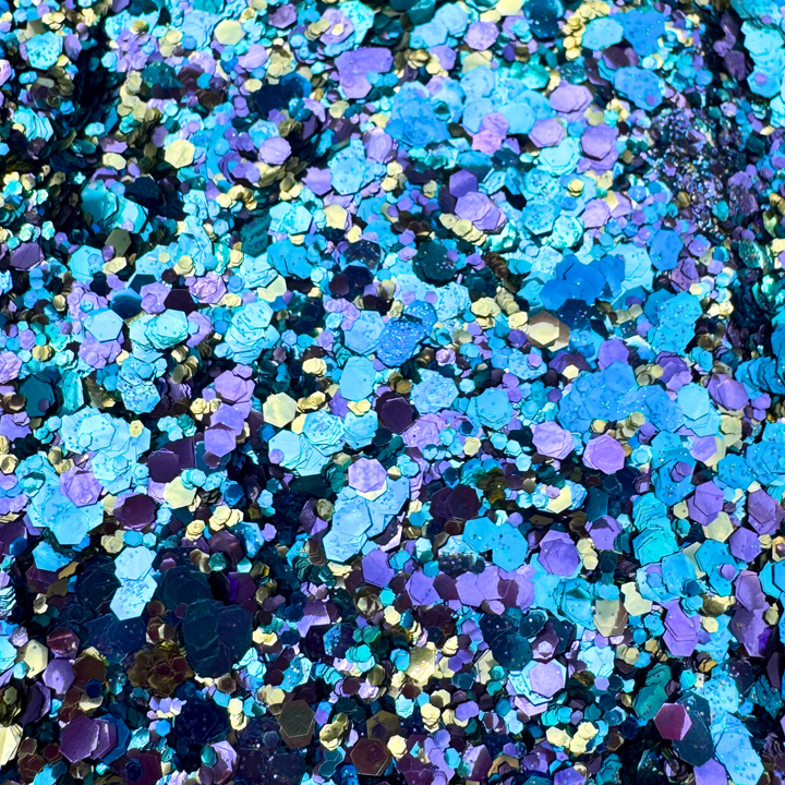 Colorful glitter mix in blue, purple, and gold on a dark background
