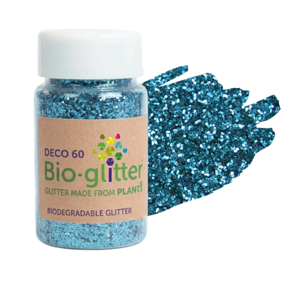 A jar of blue craft Bio-glitter with a white cap and a kraft paper label, shown next to a textured smear of the sparkling blue glitter on a white background.