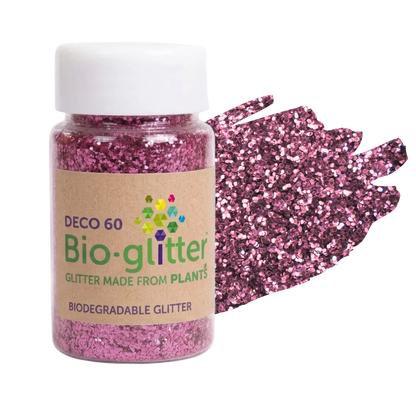 A jar of pink craft Bio-glitter with a white cap and a kraft paper label, shown next to a textured swatch of the pink glitter on a white background.