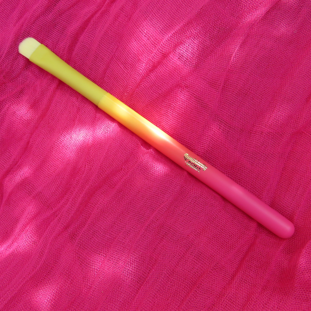 Pink and yellow makeup brush on a pink fabric background