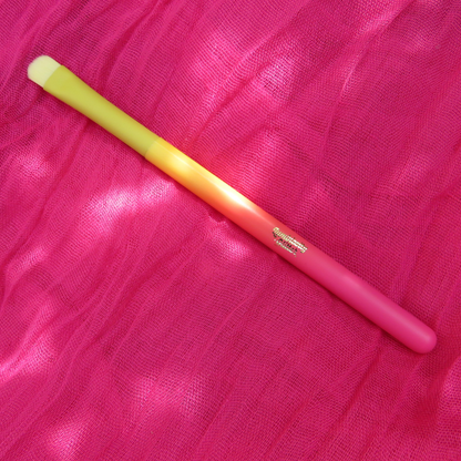 Pink and yellow makeup brush on a pink fabric background