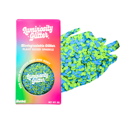 Biodegradable glitter packaging with a colorful box and green glitter on a white background