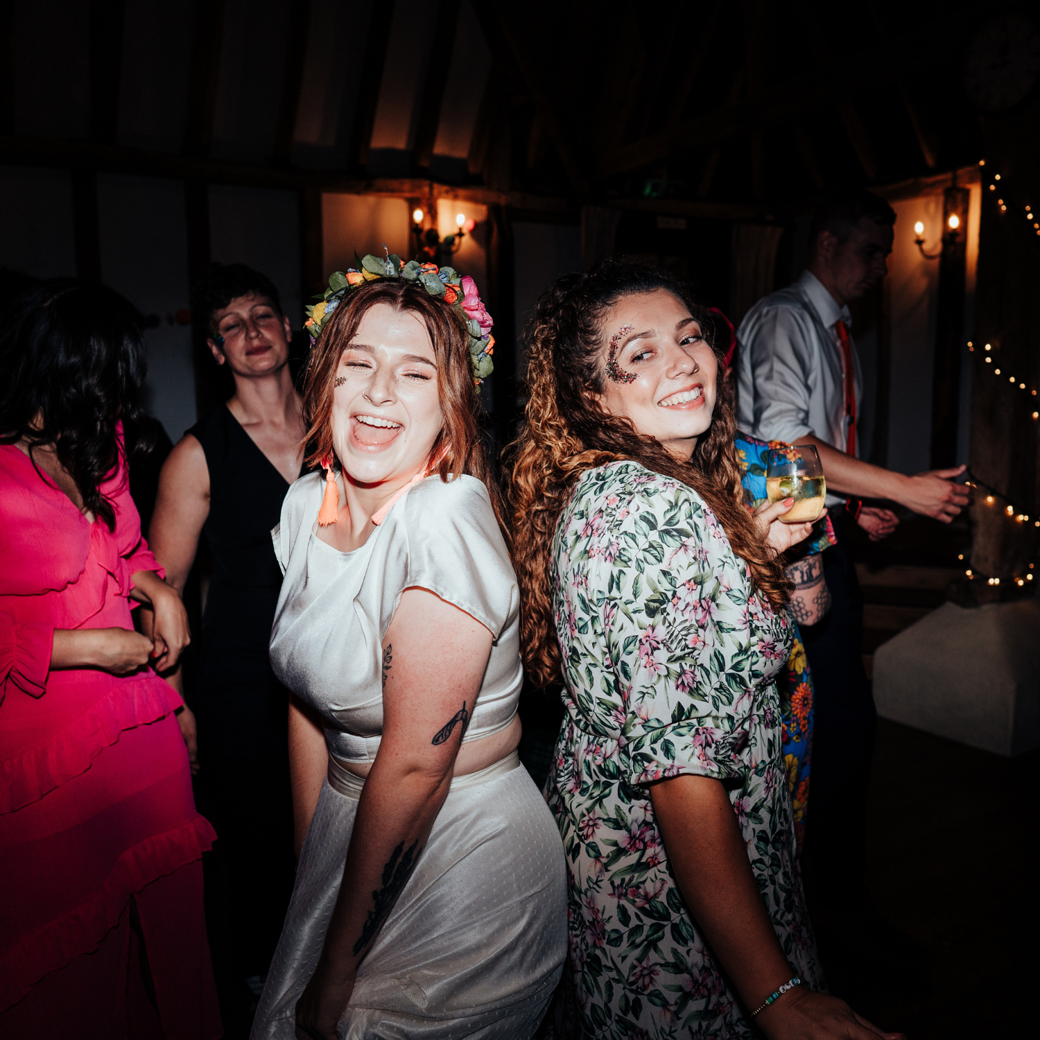 A bride and guests at a wedding dancing with face glitter on.